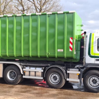Een vrachtwagen met een groene afzetcontainer