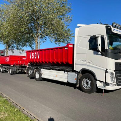 Twee rode spantencontainers van 15 m3 worden vervoerd door een vrachtwagen.