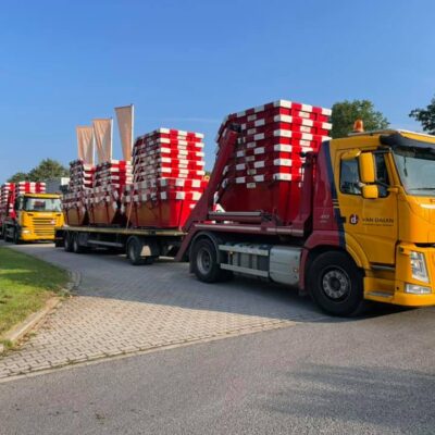 Twee vrachtwagens vervoeren een grote partij portaalarmcontainers