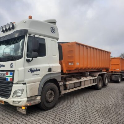 Een vrachtwagen die twee grote afzetcontainers vervoert.